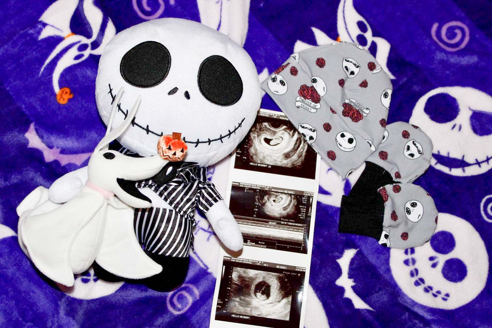 Sonogram surrounded by Nightmare Before Christmas themed stuffed toys and on top of purple blanket with the same theme.