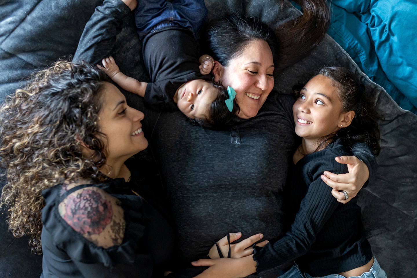 Two mom family laying down with their two daughters 