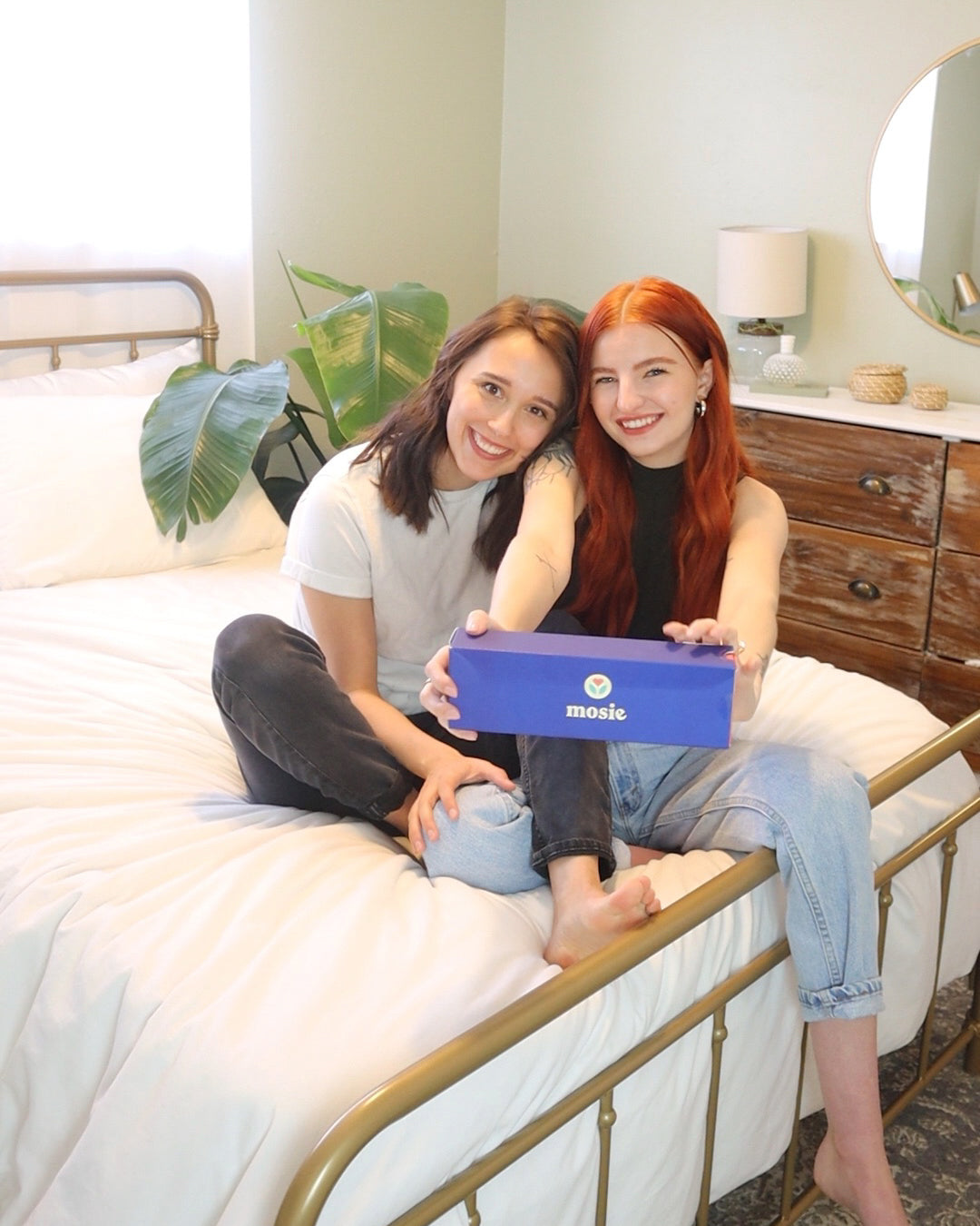 Abbie and Julia Ensign sitting on their bed holding the Mosie Kit